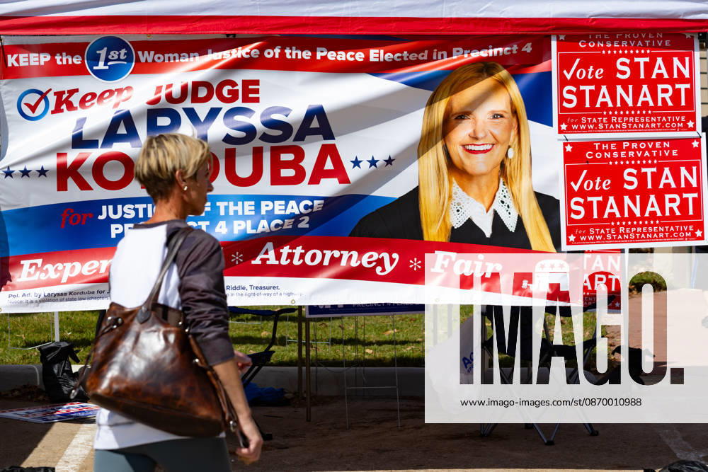 A woman walks past campaign advertising during the early voting period at the George Bush center in Houston, Texas, United States, 19 October 2026. Early voting begins in several key states in the United States !ACHTUNG: NUR REDAKTIONELLE NUTZUNG!