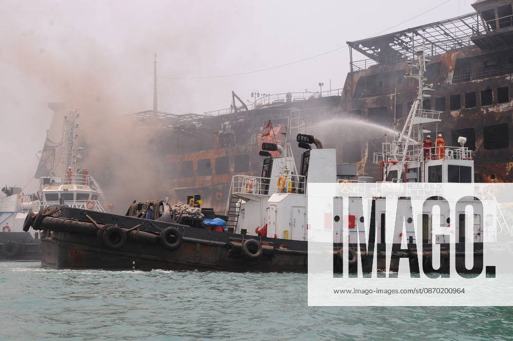 Efforts are underway to extinguish a fire that broke out on a passenger ferry in Indonesia s Cilegon PELABUHAN MERAK, CILEGON, INDONESIA - OCTOBER 21: Fireboats take turns spraying water onto the passenger ferry KMP Batumandi to cool down the vessel after it caught fire while preparing to dock off Merak Port in Cilegon, Banten, Indonesia on Wednesday, October 21, 2026. The vessel caught fire on Tuesday, October 20, and rescue operations remain underway as the ship continues to emit smoke. Water is continuously sprayed to cool the vehicle deck containing numerous cars, motorcycles, buses, and trucks, while authorities confirm no fatalities have been reported. Dasril Roszandi Anadolu Pelabuhan Merak Indonesia. Editorial use only. Please get