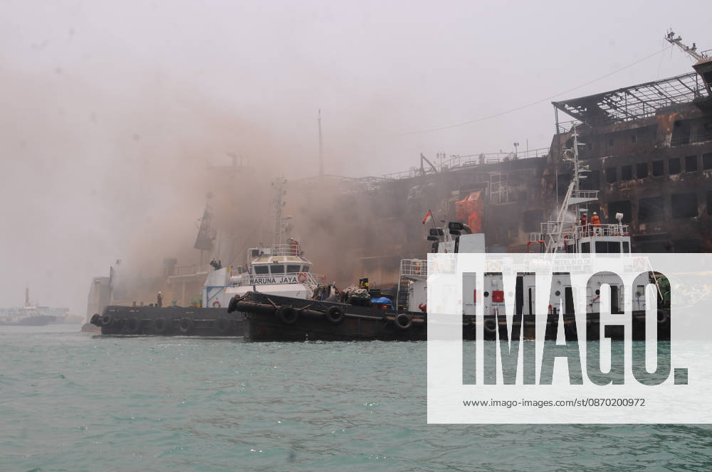 Efforts are underway to extinguish a fire that broke out on a passenger ferry in Indonesia s Cilegon PELABUHAN MERAK, CILEGON, INDONESIA - OCTOBER 21: Fireboats take turns spraying water onto the passenger ferry KMP Batumandi to cool down the vessel after it caught fire while preparing to dock off Merak Port in Cilegon, Banten, Indonesia on Wednesday, October 21, 2026. The vessel caught fire on Tuesday, October 20, and rescue operations remain underway as the ship continues to emit smoke. Water is continuously sprayed to cool the vehicle deck containing numerous cars, motorcycles, buses, and trucks, while authorities confirm no fatalities have been reported. Dasril Roszandi Anadolu Pelabuhan Merak Indonesia. Editorial use only. Please get