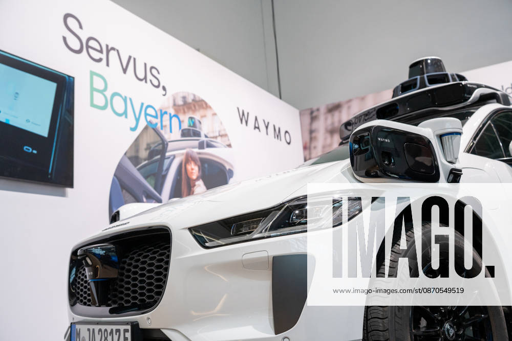 Munich, Bavaria, Germany October 23, 2026: The 2026 convention of the CSU (Christian Social Union) party at the Munich Trade Fair Center. Background image: a close-up of a white Jaguar I-PACE equipped with autonomous driving technology from the U.S. company Waymo. The electric vehicle is equipped with cameras, LiDAR, and radar sensors for AI-assisted detection of its surroundings and is designed for use as a self-driving robotaxi