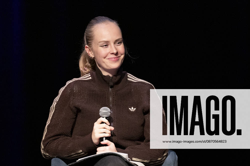 Poetry artist and author Clara LOESEL LÖSEL, smiling during her reading—a preview event for her new book, *Ich dachte, sowas fühle nur ich*—seated with a microphone; single frame, single photo, at the Theater am Tanzbrunnen, Cologne, on October 23, 2026