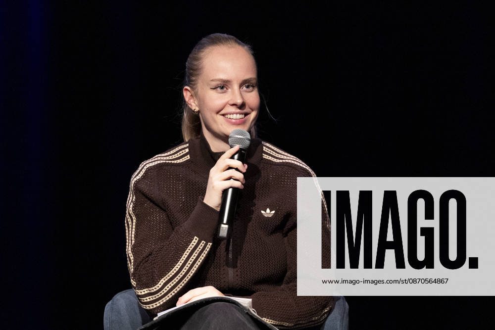 Poetry artist and author Clara LOESEL LÖSEL laughing during her reading, a preview show for her new book *Ich dachte, sowas fühle nur ich* (I Thought I Was the Only One Who Felt That Way), seated with a microphone; single frame, single photo, at the Theater am Tanzbrunnen, Cologne, on October 23, 2026