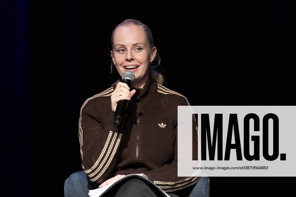 Poetry artist and author Clara LOESEL LÖSEL, smiling and joyful, during her reading—a preview event for her new book, *Ich dachte, sowas fühle nur ich*—seated with a microphone; single frame, single photo, at the Theater am Tanzbrunnen, Cologne, on October 23, 2026