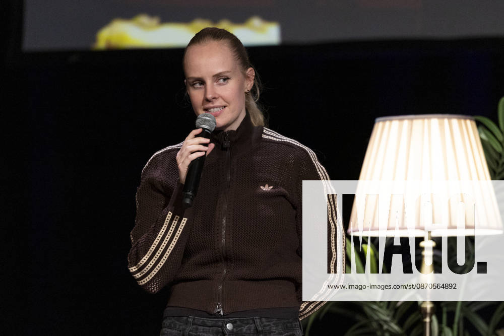 Poetry artist and author Clara LOESEL LÖSEL speaks intently during her reading—a preview of her new book, *Ich dachte, sowas fühle nur ich*—standing with a microphone, in a single frame, a single photograph, at the Theater am Tanzbrunnen, Cologne, on October 23, 2026