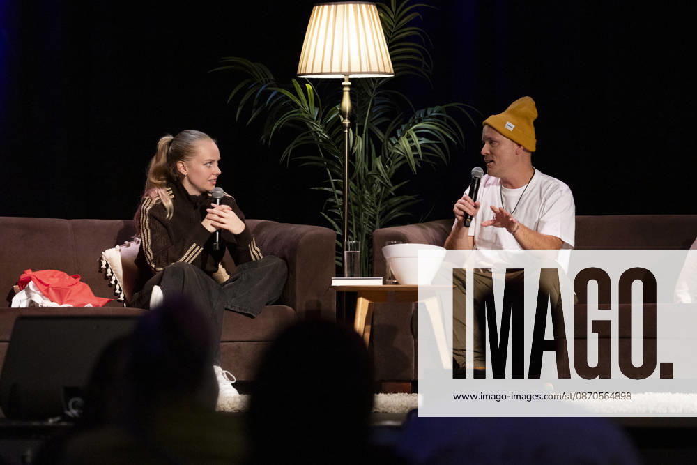 Poet and author Clara LOESEL LÖSEL (left) in conversation with author and podcaster Lars AMEND (right) during her reading—a preview event for her new book, *Ich dachte, sowas fühle nur ich*—sitting on sofas with microphones at the Theater am Tanzbrunnen, Cologne, on October 23, 2026