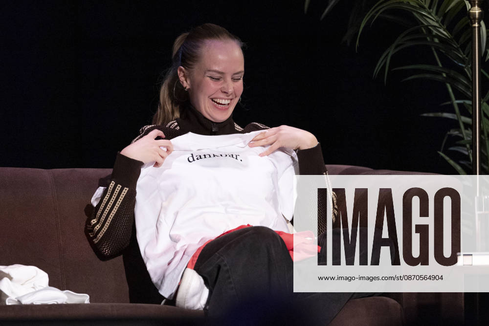 Poetry artist and author Clara LOESEL LÖSEL, wearing a T-shirt with the word grateful printed on it, during her reading—a preview event for her new book *Ich dachte, sowas fühle nur ich*—sitting on a sofa; single frame, single photo, at the Theater am Tanzbrunnen, Cologne, on October 23, 2026