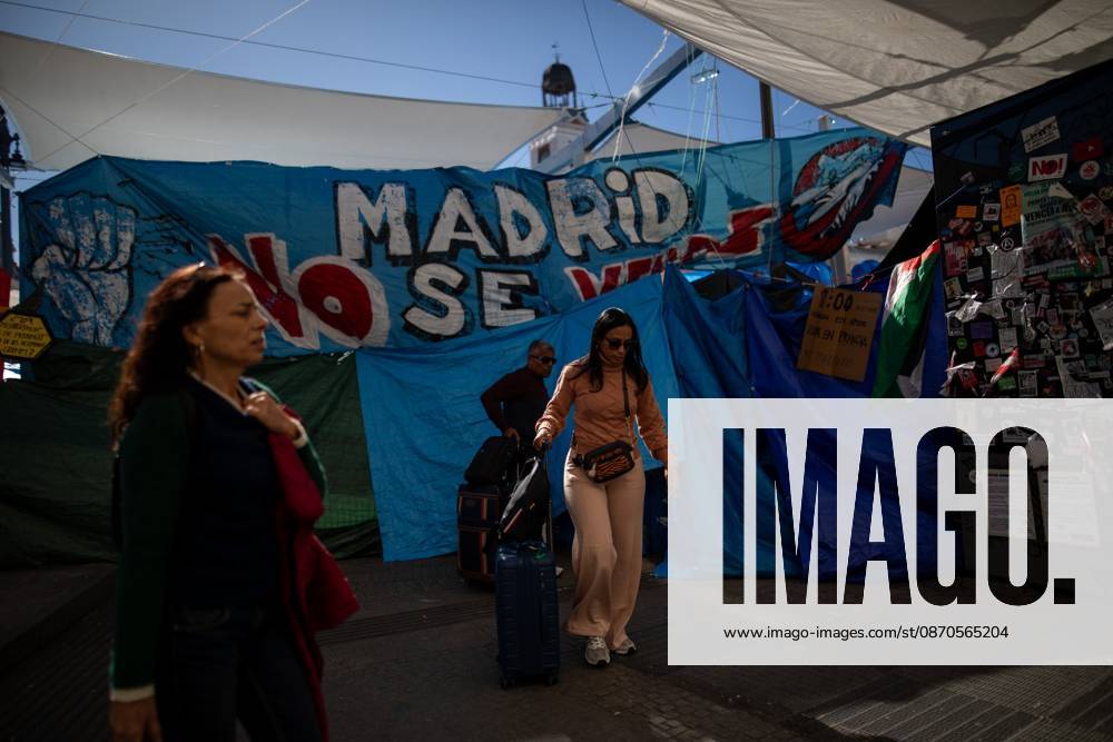 A couple walks with suitcases in front of tents set up at Puerta del Sol..Tents remain set up by housing rights activists, who organized the occupation of the square in response to the eviction of Maricarmenâ€a woman in her eightiesâ€from her home, carried out by a real estate investment fund. Madrid Spain - ZUMAs197 20261023_aaa_s197_149