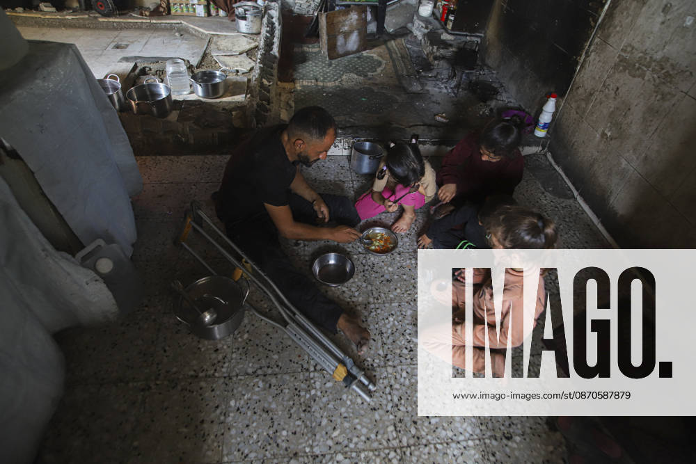 Gaza Palestinians Food Shortages 2026 A Palestinian man using crutches sits with children as they eat a meal received from a charity kitchen inside a damaged building in Jabalia Refugee Camp, northern Gaza Strip, Palestine, on October 24, 2026. The UN says widespread damage, displacement and food shortages have left families across Gaza heavily dependent on humanitarian assistance, with food distributions reduced in October amid funding constraints. Jabalia Gaza Strip Palestinian Territories