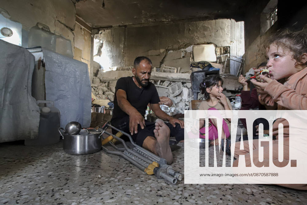 Gaza Palestinians Food Shortages 2026 A Palestinian man using crutches sits with children as they eat a meal received from a charity kitchen inside a damaged building in Jabalia Refugee Camp, northern Gaza Strip, Palestine, on October 24, 2026. The UN says widespread damage, displacement and food shortages have left families across Gaza heavily dependent on humanitarian assistance, with food distributions reduced in October amid funding constraints. Jabalia Gaza Strip Palestinian Territories