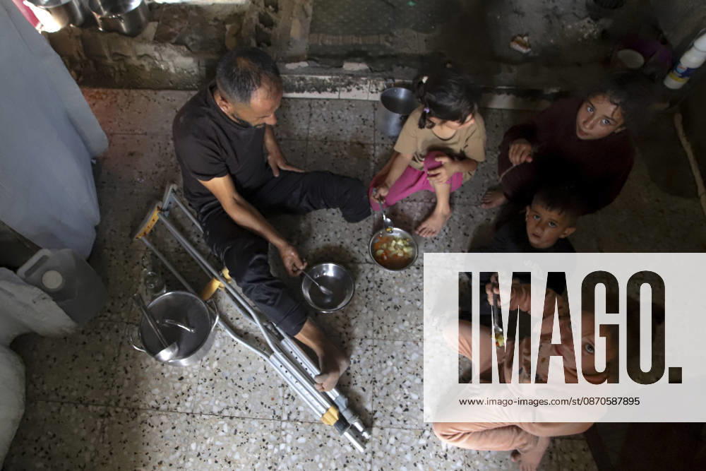 Gaza Palestinians Food Shortages 2026 A Palestinian man using crutches sits with children as they eat a meal received from a charity kitchen inside a damaged building in Jabalia Refugee Camp, northern Gaza Strip, Palestine, on October 24, 2026. The UN says widespread damage, displacement and food shortages have left families across Gaza heavily dependent on humanitarian assistance, with food distributions reduced in October amid funding constraints. Jabalia Gaza Strip Palestinian Territories