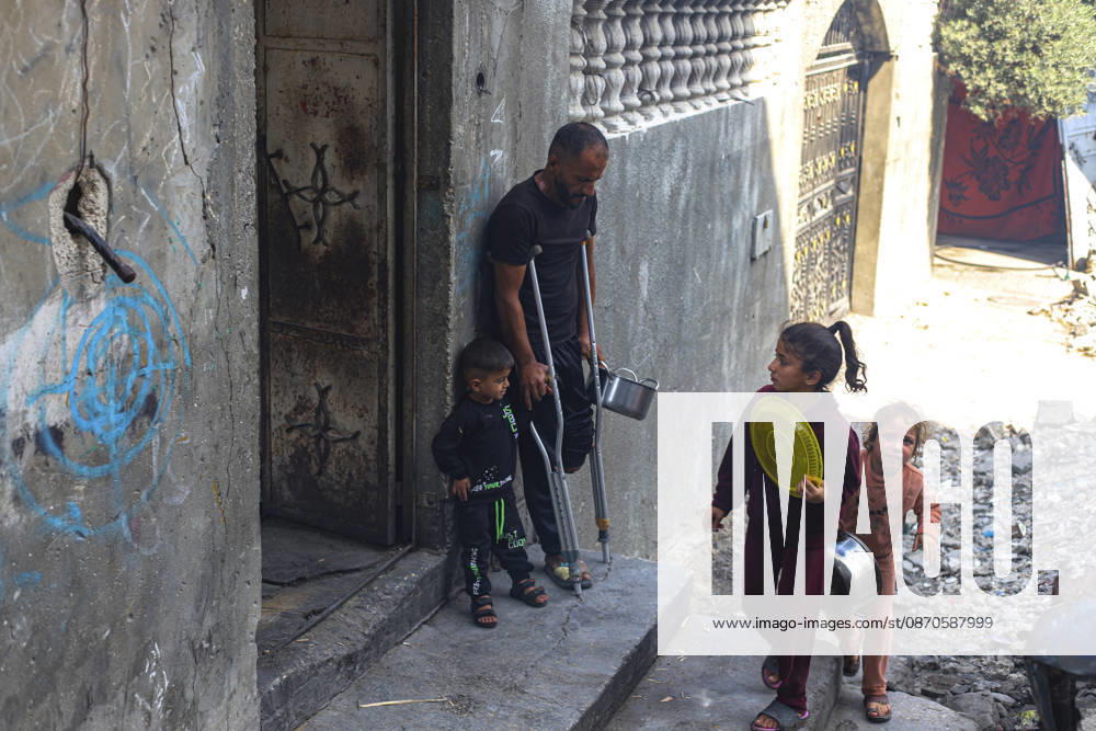 Gaza Palestinians Food Shortages 2026 A Palestinian man using crutches stands in a doorway as children pass through a damaged street in Jabalia Refugee Camp, northern Gaza Strip, Palestine, on October 24, 2026. The UN says widespread damage, displacement and food shortages have left families across Gaza heavily dependent on humanitarian assistance, with food distributions reduced in October amid funding constraints. Jabalia Gaza Strip Palestinian Territories
