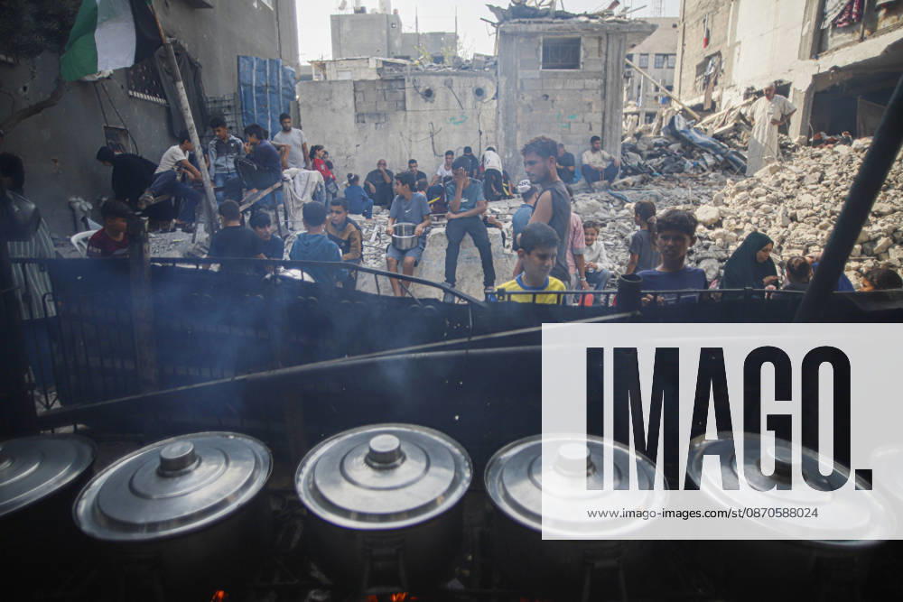 Gaza Palestinians Food Shortages 2026 Palestinians wait behind large cooking pots as food is prepared over an open flame at a charity kitchen in Jabalia Refugee Camp, northern Gaza Strip, Palestine, on October 24, 2026. Community kitchens remain a key source of food in Gaza, where UN humanitarian agencies reported cuts to cooked-meal distributions in October because of funding shortages. Jabalia Gaza Strip Palestinian Territories