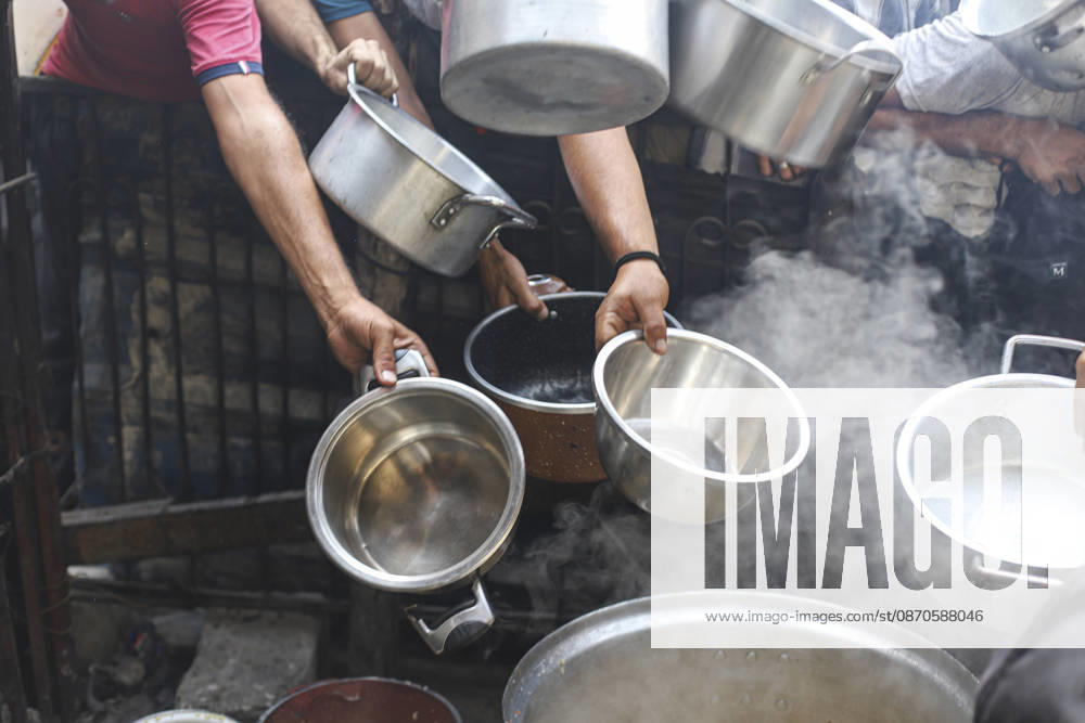 Gaza Palestinians Food Shortages 2026 Hands hold several metal bowls over steaming cooking pots during a hot meal distribution in Jabalia Refugee Camp, northern Gaza Strip, Palestine, on October 24, 2026. Community kitchens remain a key source of food in Gaza, where UN humanitarian agencies reported cuts to cooked-meal distributions in October because of funding shortages. Jabalia Gaza Strip Palestinian Territories