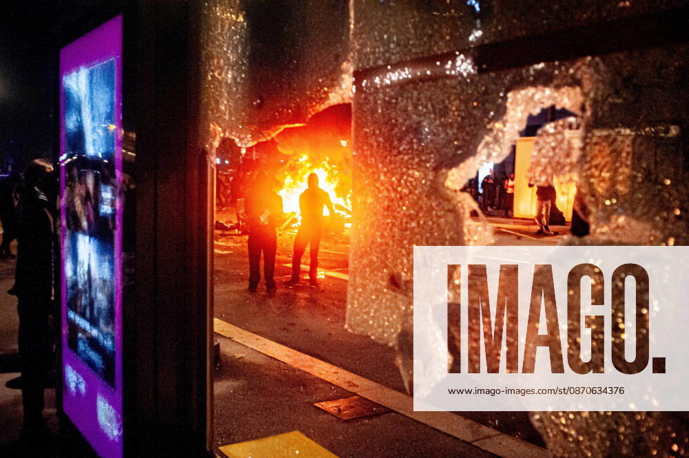 A burning barricade is seen through the shattered glass of a bus shelter amid unrest in central Barcelona. Clashes between demonstrators and police, looting and widespread vandalism were reported across the city centre overnight. Barcelona Spain - ZUMAb137 20261024_fap_b137_012