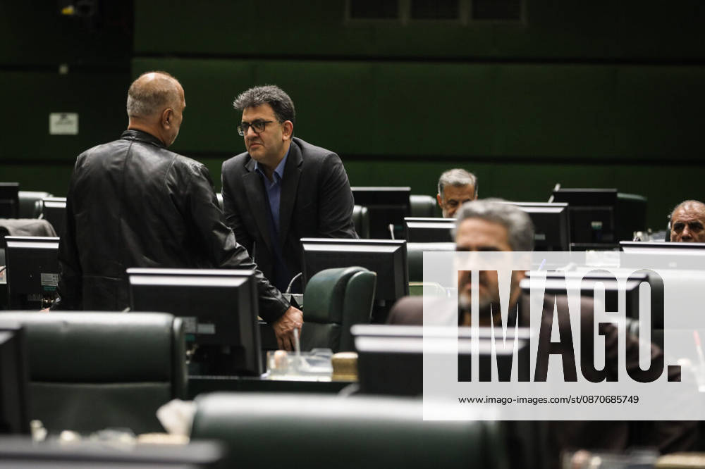 Two men speak beside the green parliamentary benches while a third suited lawmaker sits in the foreground at the Islamic Consultative Assembly in Tehran, Iran, on October 25, 2026. Parliamentary reports said more than two-thirds of lawmakers joined the October 25 open sitting of the Islamic Consultative Assembly, attending either in person or remotely. Tehran Iran - ZUMAi98_ 20261025_zih_i98_047