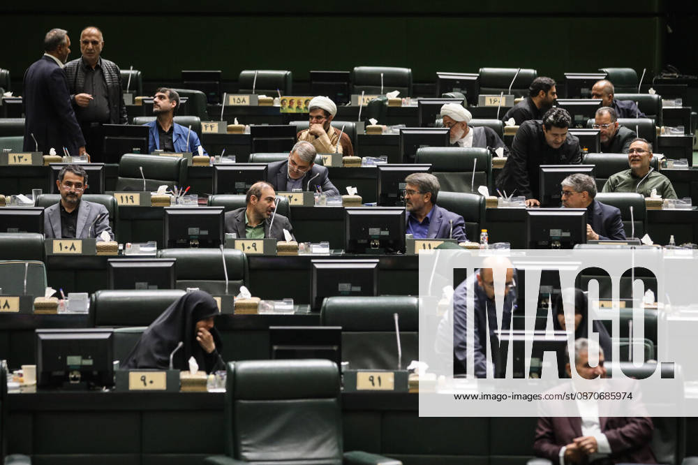 Lawmakers occupy scattered rows of numbered green desks, some speaking to colleagues and others reading documents at the Islamic Consultative Assembly in Tehran, Iran, on October 25, 2026. Parliamentary reports said more than two-thirds of lawmakers joined the October 25 open sitting of the Islamic Consultative Assembly, attending either in person or remotely. Tehran Iran - ZUMAi98_ 20261025_zih_i98_060