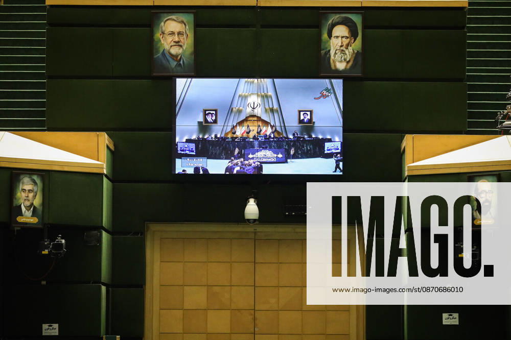 A large screen on the back wall of the parliamentary chamber displays a video image of the presiding area at the Islamic Consultative Assembly in Tehran, Iran, on October 25, 2026. The Iranian parliament held a hybrid open sitting, with some lawmakers attending in the Tehran chamber and others participating remotely, according to parliamentary reports. Tehran Iran - ZUMAi98_ 20261025_zih_i98_067