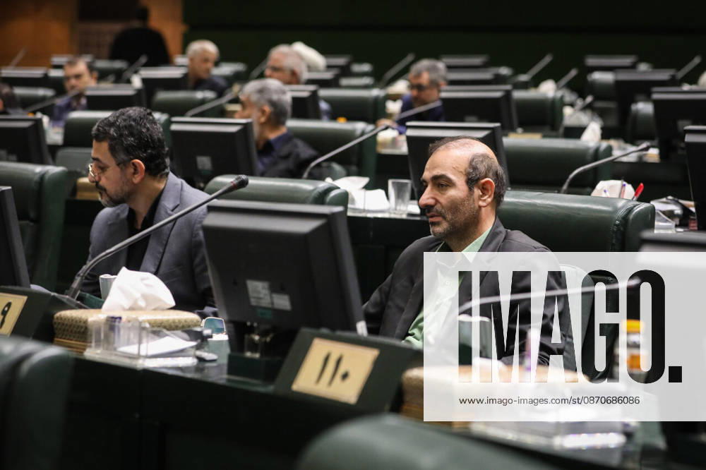 Two male lawmakers sit behind parliamentary desk monitors, one wearing a dark jacket over a green shirt at the Islamic Consultative Assembly in Tehran, Iran, on October 25, 2026. Speaker Mohammad Bagher Ghalibaf chaired the October 25 session, which combined physical attendance at the Islamic Consultative Assembly with participation by video link. Tehran Iran - ZUMAi98_ 20261025_zih_i98_085