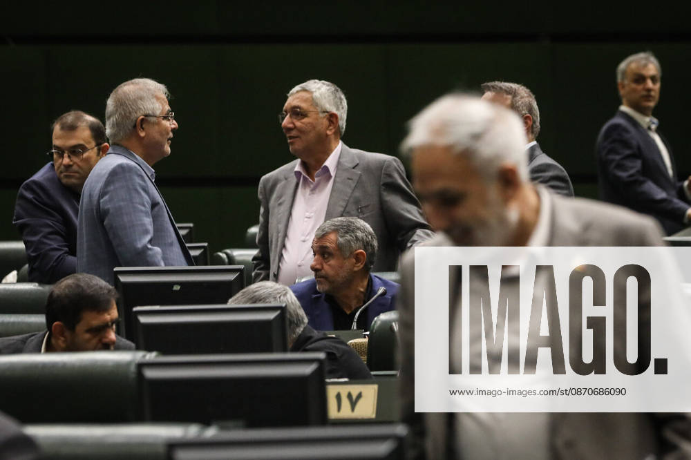 Two gray-haired men stand talking among the seats while another lawmaker crosses the foreground of the chamber at the Islamic Consultative Assembly in Tehran, Iran, on October 25, 2026. The Islamic Consultative Assembly resumed an open sitting in its Tehran chamber with a mix of in-person and remote participation, according to parliamentary reporting. Tehran Iran - ZUMAi98_ 20261025_zih_i98_089