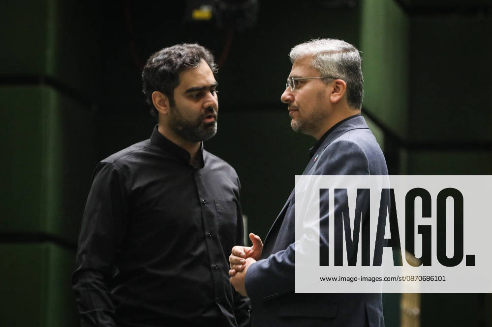 Two suited men talk face to face beside an aisle, one holding his hands together while the other listens at the Islamic Consultative Assembly in Tehran, Iran, on October 25, 2026. The Islamic Consultative Assembly resumed an open sitting in its Tehran chamber with a mix of in-person and remote participation, according to parliamentary reporting. Tehran Iran - ZUMAi98_ 20261025_zih_i98_075