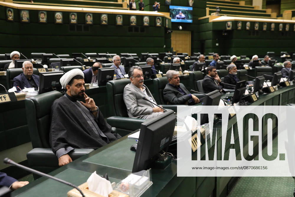 Lawmakers sit along a curved row of green benches while a cleric in a white turban occupies a front seat at the Islamic Consultative Assembly in Tehran, Iran, on October 25, 2026. The Iranian parliament held a hybrid open sitting, with some lawmakers attending in the Tehran chamber and others participating remotely, according to parliamentary reports. Tehran Iran - ZUMAi98_ 20261025_zih_i98_098