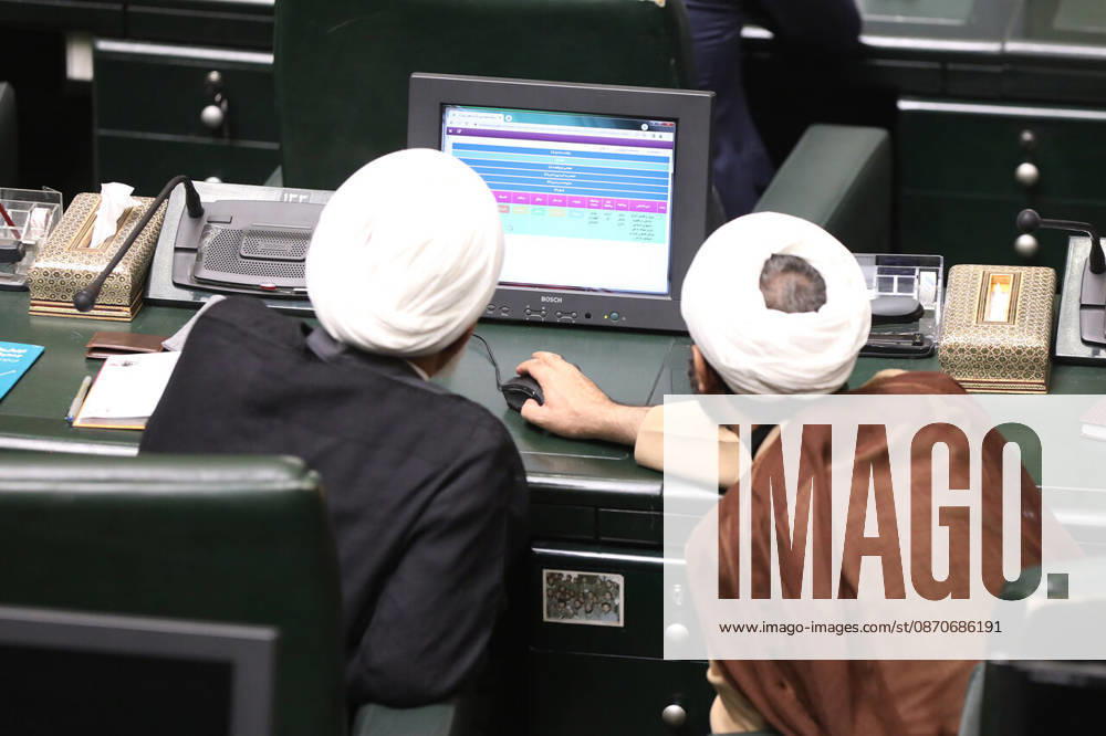 Two turbaned clerics lean over an electronic display showing colored rows of information at a parliamentary desk at the Islamic Consultative Assembly in Tehran, Iran, on October 25, 2026. The Iranian parliament held a hybrid open sitting, with some lawmakers attending in the Tehran chamber and others participating remotely, according to parliamentary reports. Tehran Iran - ZUMAi98_ 20261025_zih_i98_112