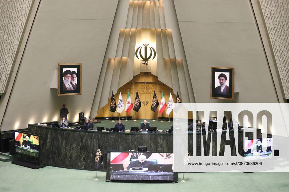 The presiding platform appears beneath the national emblem and two framed portraits, with video displays at its base at the Islamic Consultative Assembly in Tehran, Iran, on October 25, 2026. The Islamic Consultative Assembly resumed an open sitting in its Tehran chamber with a mix of in-person and remote participation, according to parliamentary reporting. Tehran Iran - ZUMAi98_ 20261025_zih_i98_123