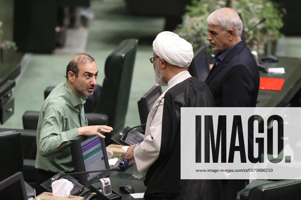 A man in a pale green shirt talks to a white-turbaned cleric, with a gray-haired lawmaker standing behind them at the Islamic Consultative Assembly in Tehran, Iran, on October 25, 2026. Parliamentary reports said more than two-thirds of lawmakers joined the October 25 open sitting of the Islamic Consultative Assembly, attending either in person or remotely. Tehran Iran - ZUMAi98_ 20261025_zih_i98_126