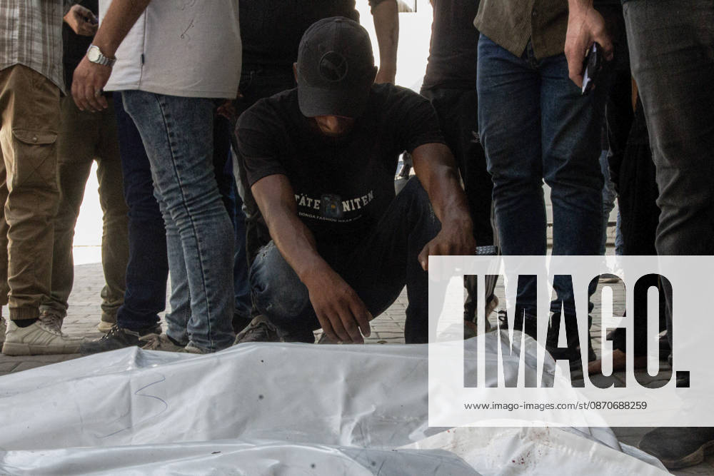 Gaza Israeli University Strike 2026 A Palestinian mourner crouches beside a white body bag while others stand nearby ahead of a funeral in Gaza City, Palestine, on October 25, 2026. According to information provided by local sources, three Islamic University guards, Ashraf Dahlan, Shadi Abu Ataya and Sami Baroud, were killed and others injured in an Israeli strike on the university campus in western Gaza City. Palestinian media reported that a second drone strike hit the campus after an earlier attack injured several people and prompted the university to suspend activities. Gaza Gaza Strip Palestinian Territories