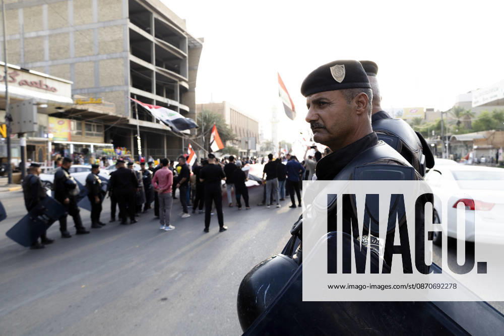 Najaf Iraq October Protest A security officer stands near demonstrators during a protest in Najaf, Iraq on October 25, 2026. The protest marked the seventh anniversary of the October 2019 protest movement, with participants calling for political reform, anti-corruption measures, improved public services and more jobs. Najaf Najaf Iraq