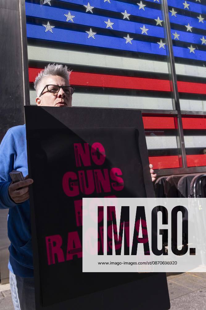 A protester holds a sign that reads NO GUNS FOR RACISTS joining demonstrators with the anti-gun violence organization Gays Against Guns under the Times Square US Army Recruiting Station LED American flag to denounce U.S. Immigration and Customs Enforcement (ICE,) President Trump s immigrant detention and mass deportation policies, and to memorialize the people killed by Federal immigration agents. New York USA - ZUMAr174 20261025_znp_r174_001