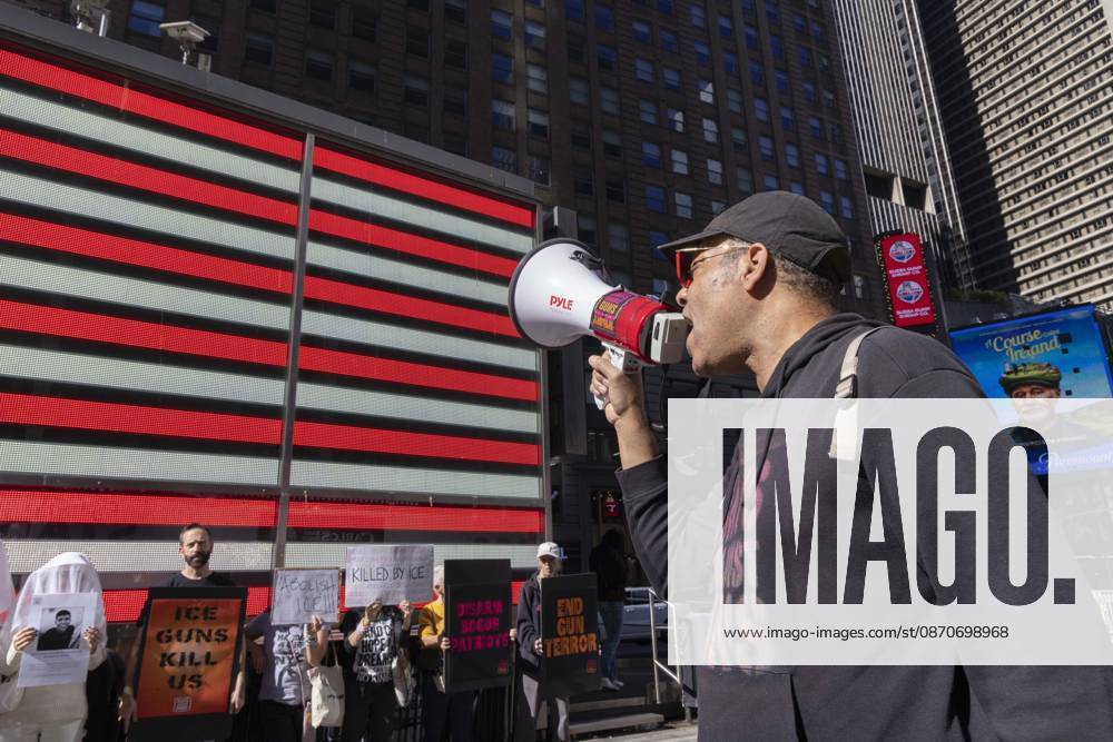 JAY W. WALKER, President of Gays Against Guns leads chants at a demonstration under the Times Square US Army Recruiting Station LED American flag to denounce U.S. Immigration and Customs Enforcement (ICE) and President Trump s immigrant detention and mass deportation policies. People dressed in white shrouds are Human Beings, memorializing people killed by gun violence from Federal immigration agents by holding signs with their images and names. Protesters hold signs that read ICE GUNS KILL US KILLED BY ICE DISARM BOGUS PATRIOTS END GUN TERROR. New York USA - ZUMAr174 20261025_znp_r174_004