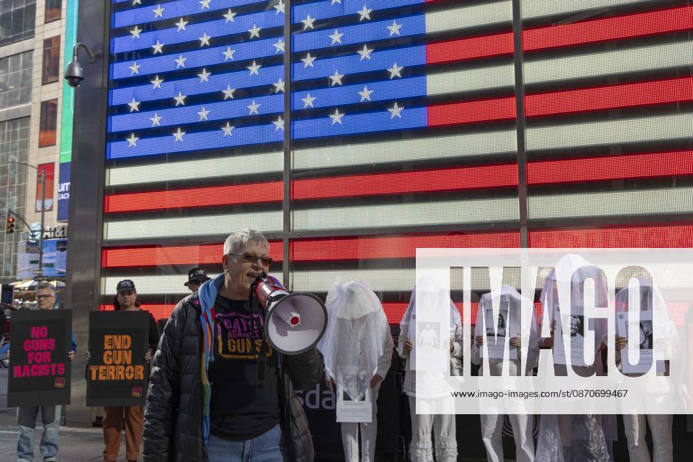 Demonstrators with the anti-gun violence organization Gays Against Guns protest under the Times Square US Army Recruiting Station LED American flag to denounce U.S. Immigration and Customs Enforcement (ICE) and President Trump s immigrant detention and mass deportation policies. People dressed in white shrouds are Human Beings, memorializing people killed by gun violence from Federal immigration agents by holding signs with their images and names. Protesters chant holding signs that read NO GUNS FOR RACISTS END GUN TERROR. New York USA - ZUMAr174 20261025_znp_r174_019