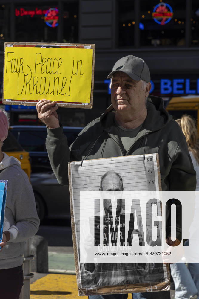A demonstrator stands with a group of protesters in Times Square holding signs that read Fair Peace in Ukraine! and a sign with an image of President of Russia V. Putin in a mugshot that reads A WAR CRIMINAL. New York USA - ZUMAr174 20261025_znp_r174_027