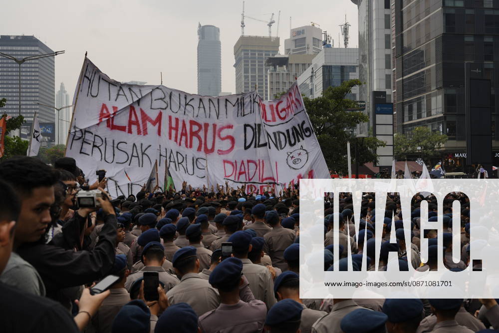 Student protesters gather behind a large banner bearing messages about environmental destruction as Indonesian police officers stand between them and the crowd during a demonstration near thamrin Jakarta Indonesia - ZUMAm265 20261028_zip_m265_004