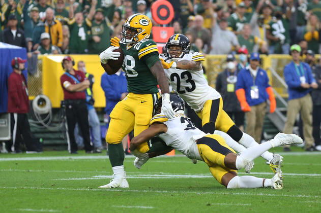 GREEN BAY, WI - OCTOBER 03: Green Bay Packers running back A.J. Dillon (28) carries tacklers downfield during a game between the Green Bay Packers and the Pittsburgh Steelers at Lambeau Field on October 3, 2021 in Green Bay, WI. (Photo by Larry Radloff Icon Sportswire) NFL, American Football Herren, USA OCT 03 Steelers at Packers Icon2110032771