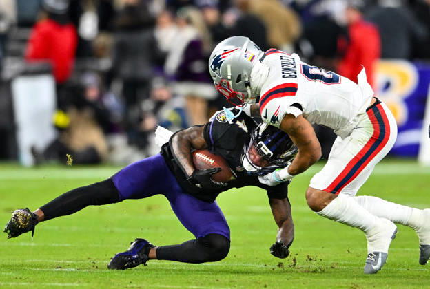 Baltimore Ravens wide receiver Zay Flowers (4) is tackled by New England Patriots cornerback Christian Gonzalez (0) after a first down pass reception during the first quarter at M&T Bank Stadium in Baltimore, Maryland, on Sunday, December 21, 2025.  BAL20251221122 DAVIDxTULIS