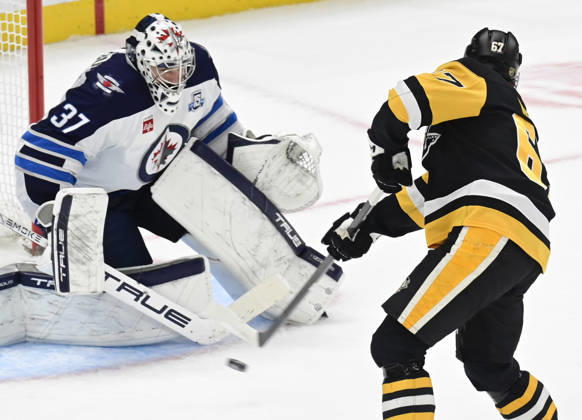 Pittsburgh Penguins right wing Rickard Rakell (67) scores on Winnipeg Jets goaltender Connor Hellebuyck (37) during the overtime penalty shot shootout in the Pittsburgh Penguins 5-4 win at PPG Paints Arena in Pittsburgh on Saturday, March 21, 2026.  PIT2026032113 ARCHIExCARPENTER