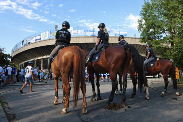 Soccer, Men s, Bavarian Regional League, 2026–2027 Season, TSV 1860 Munich vs. FC Augsburg II, Grünwalder Stadium: Here, a mounted police unit, police horses, police, security match, high-security match, danger, fans, security—with the Westkurve of the Grünwalder Stadium in Munich in the background