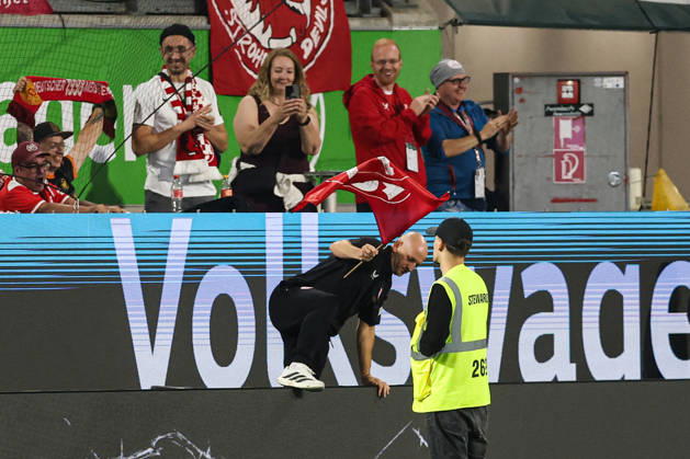 Coach Torsten Lieberknecht of 1. FC Kaiserslautern holding a 1. FC Kaiserslautern flag after the final whistle of the 2026–2027 Bundesliga match between VfL Wolfsburg and 1. FC Kaiserslautern at the Volkswagen Arena in Wolfsburg. Soccer, Man,Men, Germany, August 8, 2026