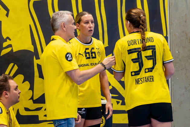 Dortmund, October 7, 2026, Handball, Women’s, Alsco Women’s Handball Bundesliga, Matchday 5, BVB Borussia Dortmund vs. Buxtehuder SV—A conversation on the players’ bench between Guro Nestaker (BVB, 33), Dana Bleckmann (BVB, 66), and Kay Rothenpieler (coach, BVB Dortmund) at the Wellinghofen Sports Hall in North Rhine-Westphalia, Germany