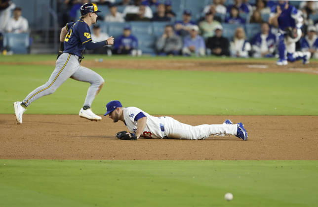 Los Angeles Dodgers third baseman Max Muncy (13) dives for a sharp grounder by Milwaukee Brewers Joey Ortiz as Brewers Cooper Pratt races past to score in the ninth inning in the MLB, Baseball Herren, USA National League Championship Series playoffs at Dodger Stadium in Los Angeles, California, on Wednesday, October 14, 2026.  LAP20261014742 CAROLINExBREHMAN