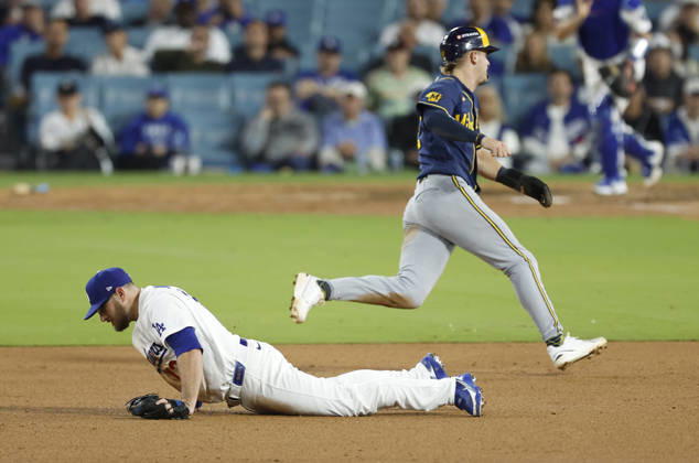 Los Angeles Dodgers third baseman Max Muncy (13) dives for a sharp grounder by Milwaukee Brewers Joey Ortiz as Brewers Cooper Pratt races past to score in the ninth inning in the MLB, Baseball Herren, USA National League Championship Series playoffs at Dodger Stadium in Los Angeles, California, on Wednesday, October 14, 2026.  LAP20261014743 CAROLINExBREHMAN