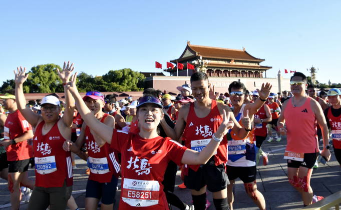 (261018) -- BEIJING, Oct. 18, 2026 -- Runners waves to cameras as they compete during the 2026 Beijing Marathon & National Marathon Championships in Beijing, capital of China, Oct. 18, 2026. ) (SP)CHINA-BEIJING-2026 BEIJING MARATHON(CN) LixXin 