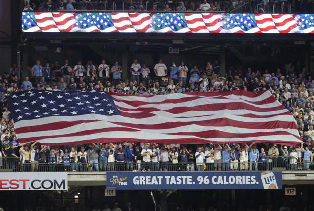 An American flag is unfurled in the stands for the singing of the National Anthem before the start of game one of the 2026 MLB, Baseball Herren, USA World Series between Milwaukee Brewers and the Tampa Bay Rays at American Family Field in Milwaukee, Wisconsin, on Friday, October 23, 2026.  MIL20261023702 TANNENxMAURY