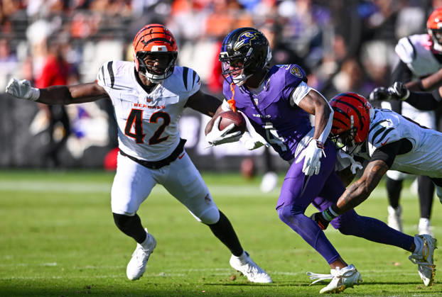 Baltimore Ravens wide receiver Zay Flowers (4) is pursued by Cincinnati Bengals safety Bryan Cook (R) and inside linebacker Oren Burks (42) during the fourth quarter at M&T Bank Stadium in Baltimore, Maryland, on Sunday, October 25, 2026. Cincinnati won 35-13.  BAL20261025122 DAVIDxTULIS