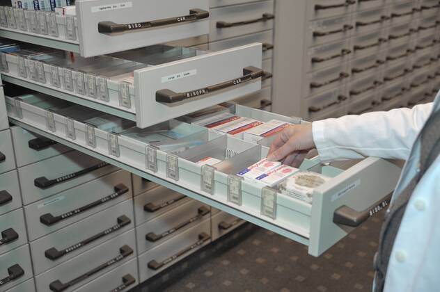 Hand nimmt Medikament aus Apothekerschrank