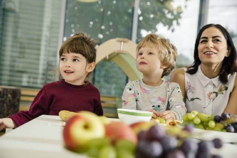 Children and teacher sitting at table with fruit in kindergarten model released Symbolfoto property released  MFF04072