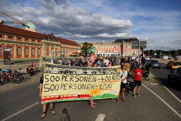 Demonstrators stand with banner 500 people 400 cars 500 people 1 train on Breite Straße as part of Students for Future bike demo Without kerosene to Berlin during a stop in Potsdam, August 31, 2022 Students for Future Without kerosene to Berlin