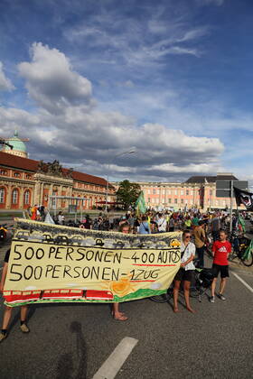 Demonstrators stand with banner 500 people 400 cars 500 people 1 train on Breite Straße as part of Students for Future bike demo Without kerosene to Berlin during a stop in Potsdam, August 31, 2022 Students for Future Without kerosene to Berlin